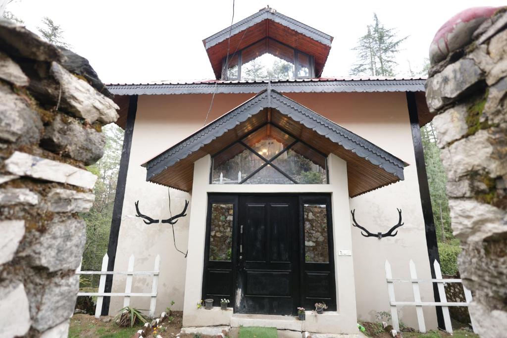 a small white house with a black door at The Woodlane Cottage in Kūfrī