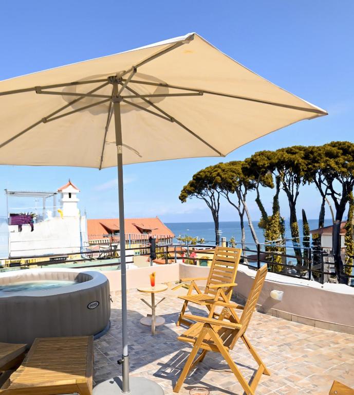 an umbrella and two chairs and a table and a tub at Il Vicoletto sul Mare in Casamicciola Terme