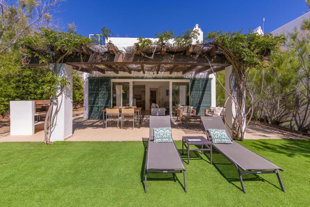 a pergola with chairs and a table in a yard at Biniancolla Ginesta in Biniancolla