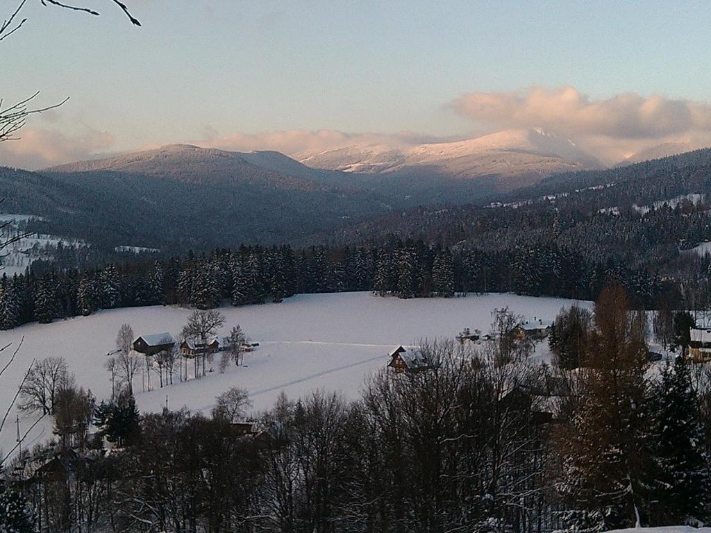 a view of a snow covered field with mountains at Apartmány Kuřátko in Benecko