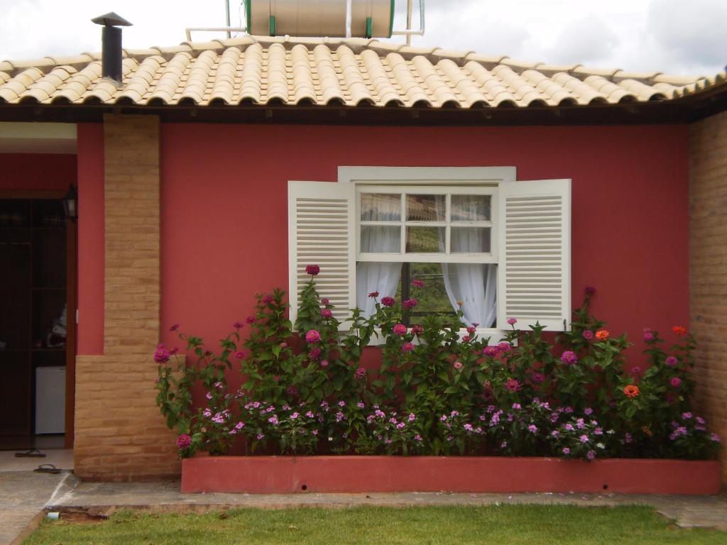 Belo Vale的住宿－Pousada Princesa Do Vale，红色的房子,有窗户和鲜花