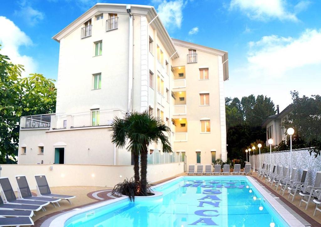 a hotel with a swimming pool in front of a building at Hotel San Carlo in Cesenatico