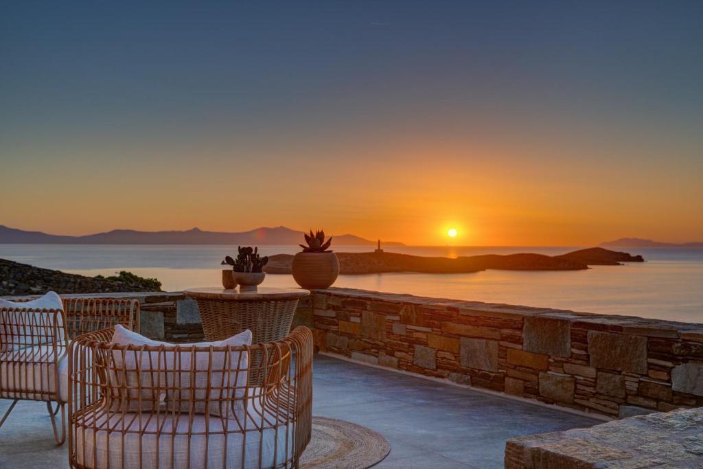 a patio with chairs and a sunset in the background at La VILLA DELLE TORRI in Ermoupoli