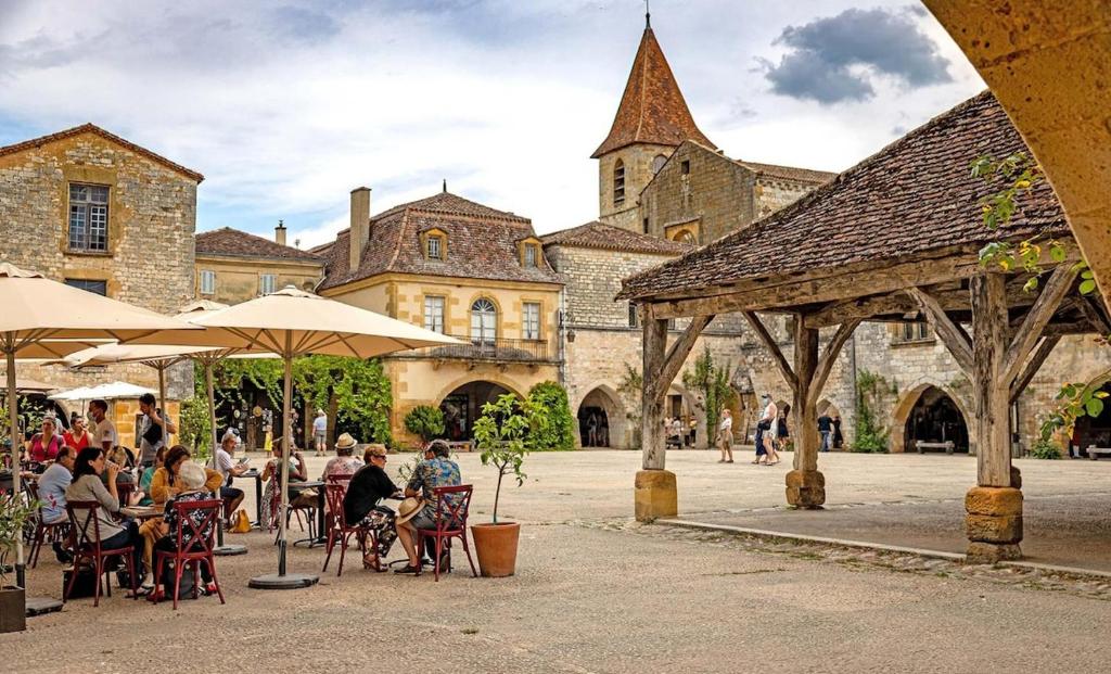 a group of people sitting at tables in front of a building at Maison Françoise in Monpazier