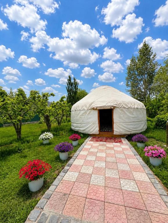 a yurt in a field with flowers in pots at Marjan Guest House in Bokonbayevo