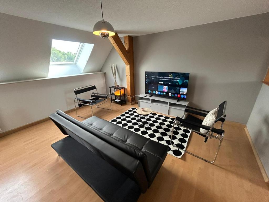 a living room with a black couch and a tv at Stadtloft am Schillerpark in Dessau