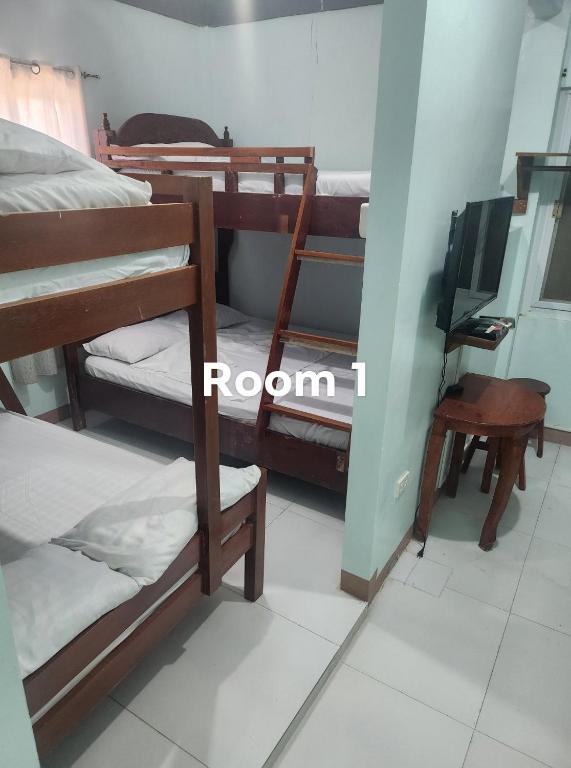 a room with bunk beds and a desk and a television at Yasmin's Transient House in Pagudpud