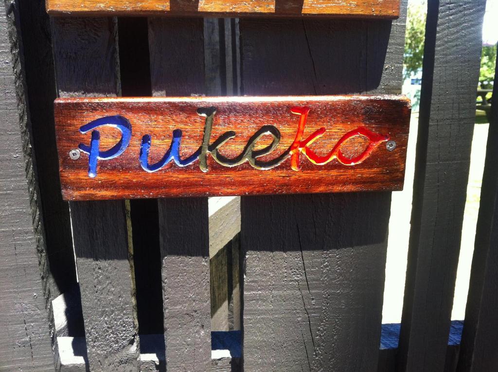a wooden sign on a fence with the word pulao at Pukeko on Bay in Tauranga