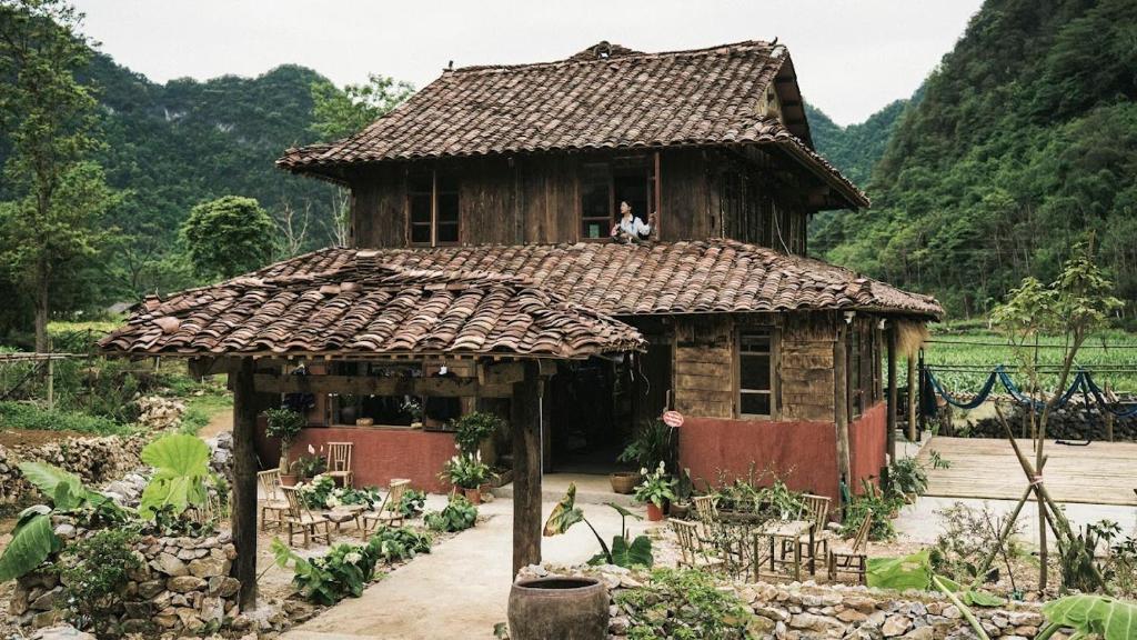 an old house with a person sitting in a window at Nùng Indigo in Cao Bằng