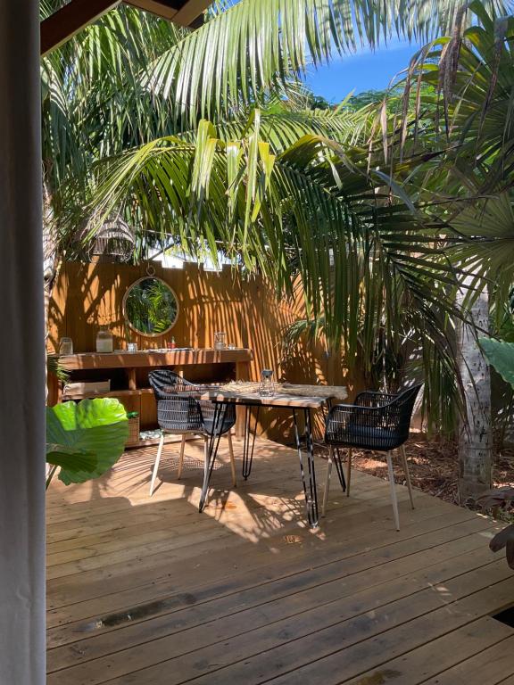 a patio with a table and chairs on a wooden deck at Tiny du lagon in Saint-Paul