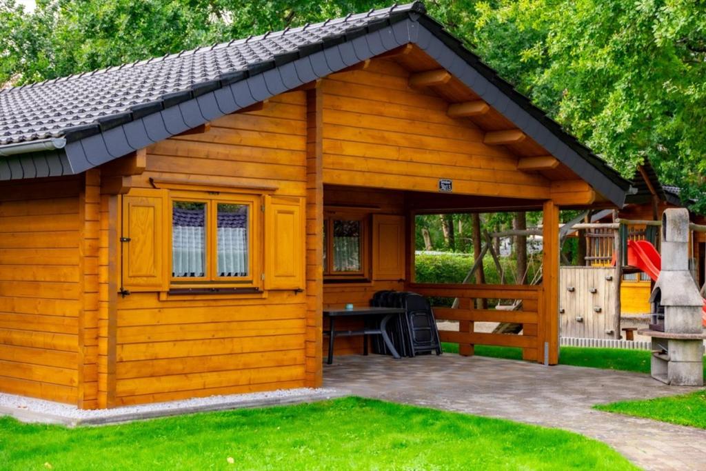 a small wooden cabin with a patio in a yard at Waldsiedlung - Haus 13 in Großkoschen