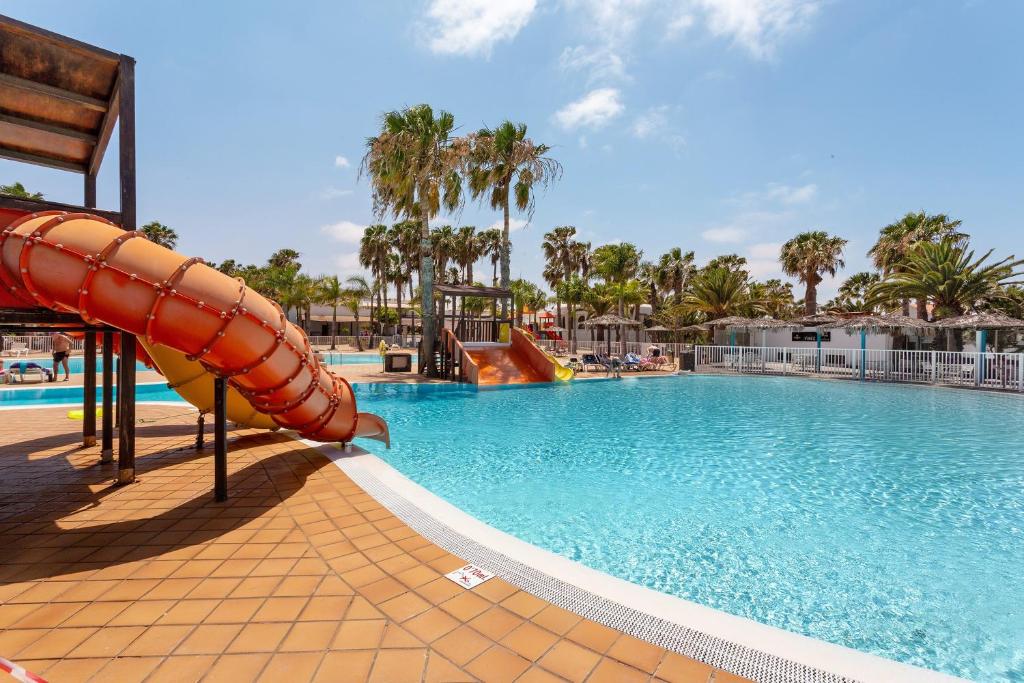 a pool with a water slide in a resort at Oasis Duna _ Estrella Del Mar Pool in Corralejo