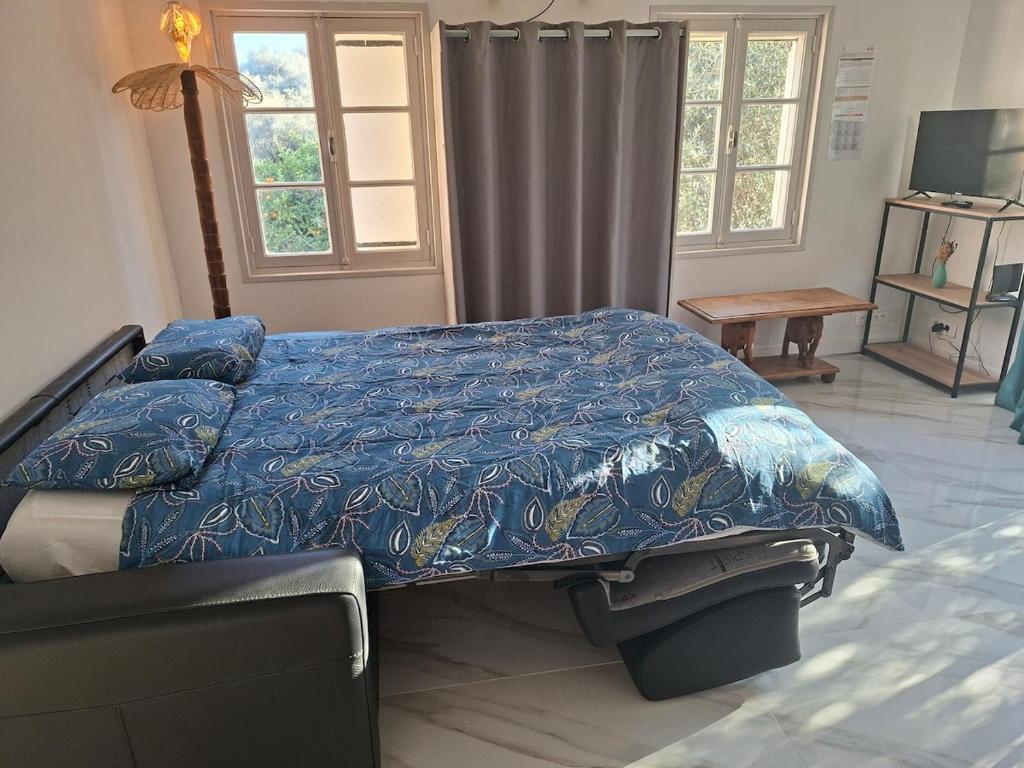 a bedroom with a bed with a blue comforter at comfortable studio in Grasse