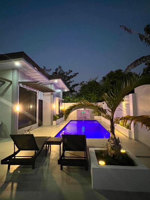 a patio with chairs and a swimming pool at night at Rams home in Moalboal
