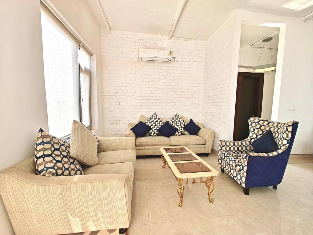 a living room with couches and chairs and a table at Oasis Murthal Open Field Views in Indraprast