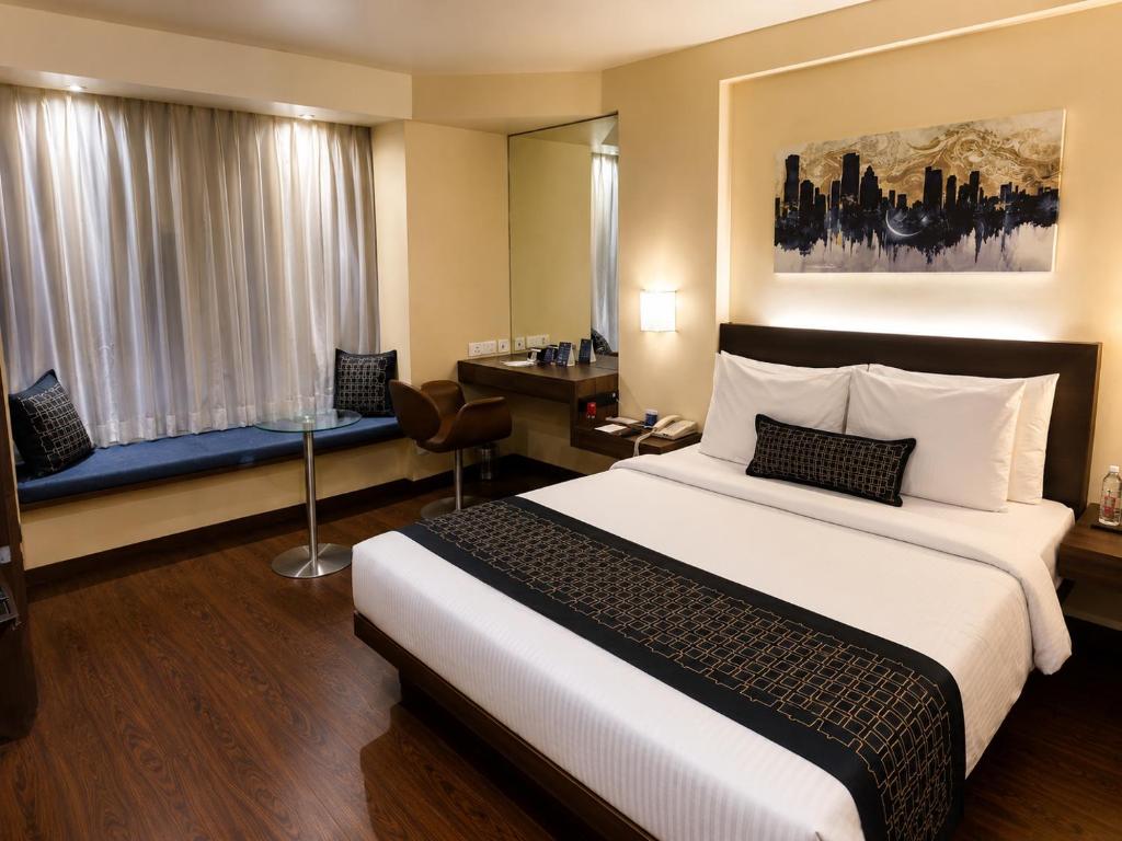 a hotel room with a large bed and a desk at Marasa Sarovar Portico -Rajkot in Rajkot