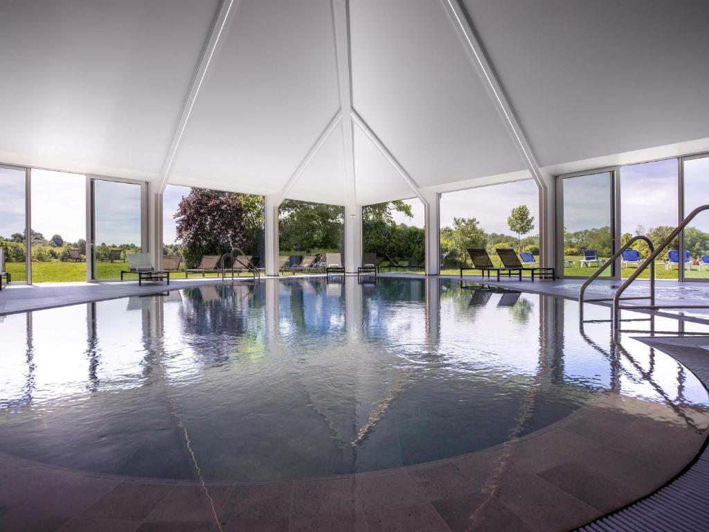 an empty swimming pool in a marquee with windows at Mercure Luxembourg Kikuoka Golf & Spa in Canach