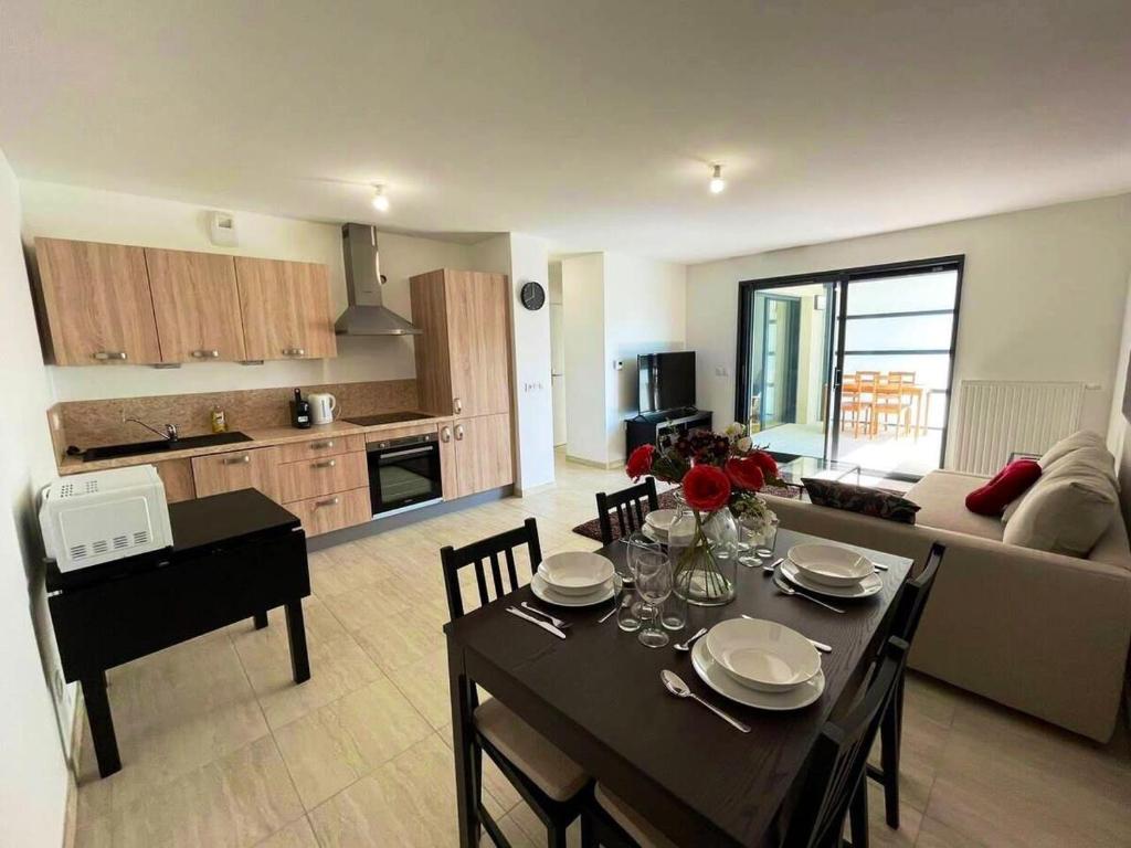 a living room with a dining table and a kitchen at Apparté - Appartement proche Genève et Palexpo in Ferney-Voltaire