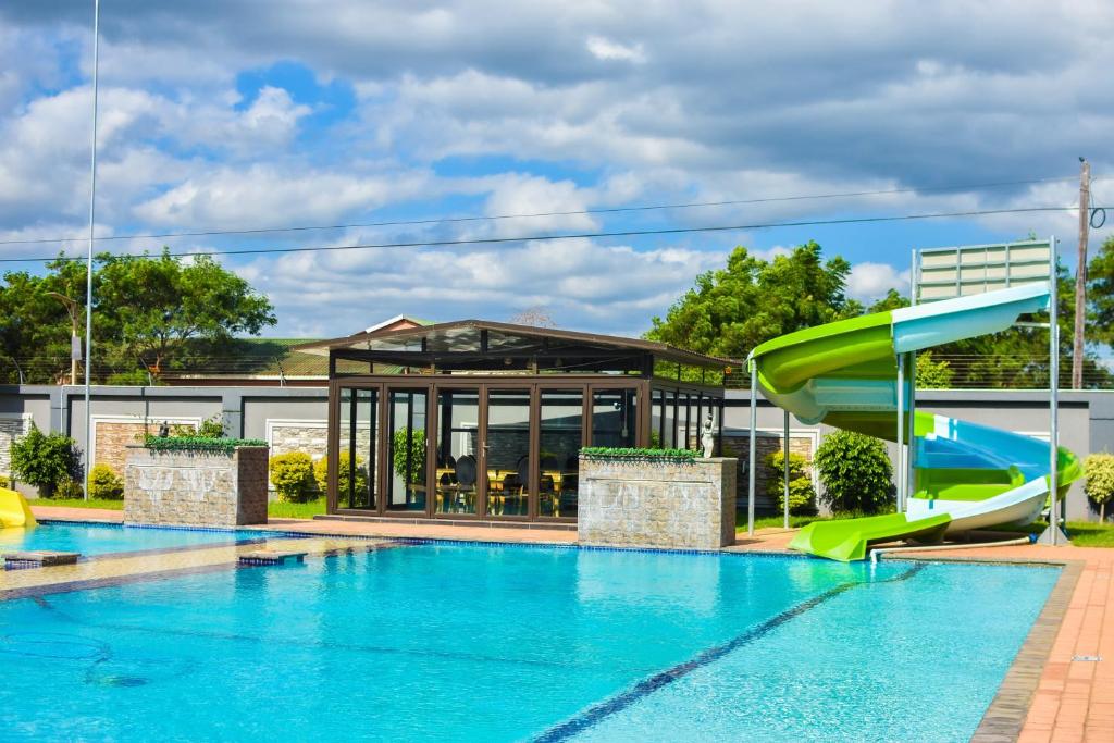 a swimming pool with a slide in front of a building at MKHUZE INN in Mkuze