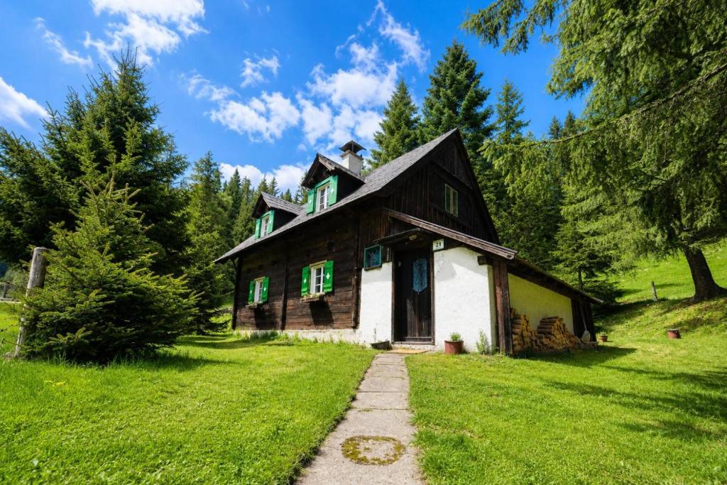 an old house with green windows on a green field at Almhütte am Steirischen Seeberg in Turnau