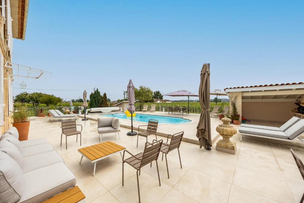 a patio with a couch and chairs and a pool at La Maison Blanche in Saint-Sulpice-de-Faleyrens