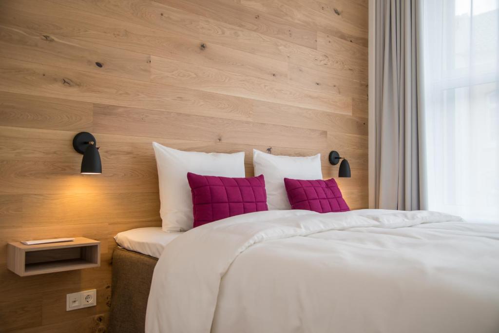 ein Schlafzimmer mit einem großen Bett mit lila Kissen in der Unterkunft Hotel Alte Post Flensburg in Flensburg