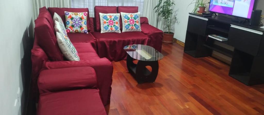 a living room with a red couch and a table at LUANAIRAM Home in Cusco