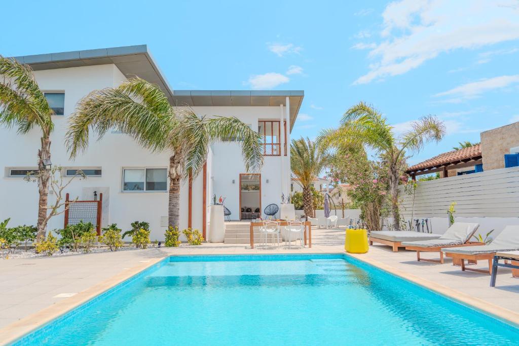 a pool in front of a house with palm trees at Seaside Hideaway Villa in Perivolia