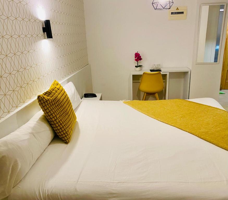 a bedroom with a large white bed with a yellow pillow at Hotel Felix in Lorca