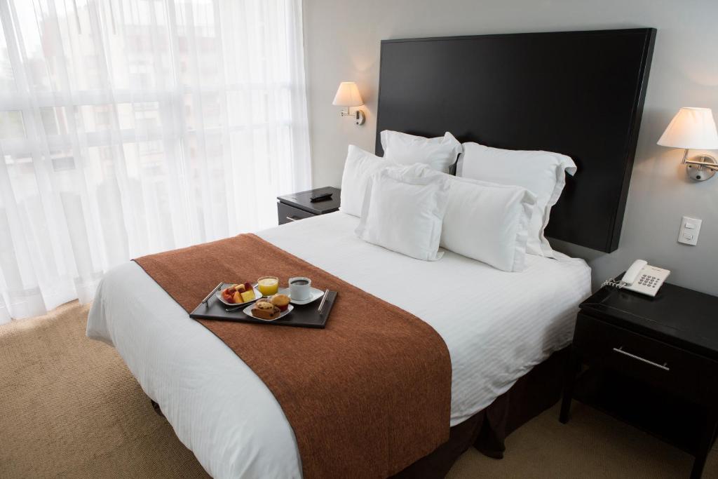 a hotel room with a bed with a tray of food on it at Suites Parioli in Mexico City