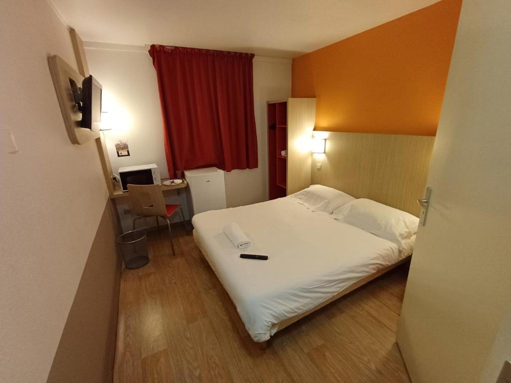 a hotel room with a white bed and a desk at Hôtel Toulouse Labège in Labège