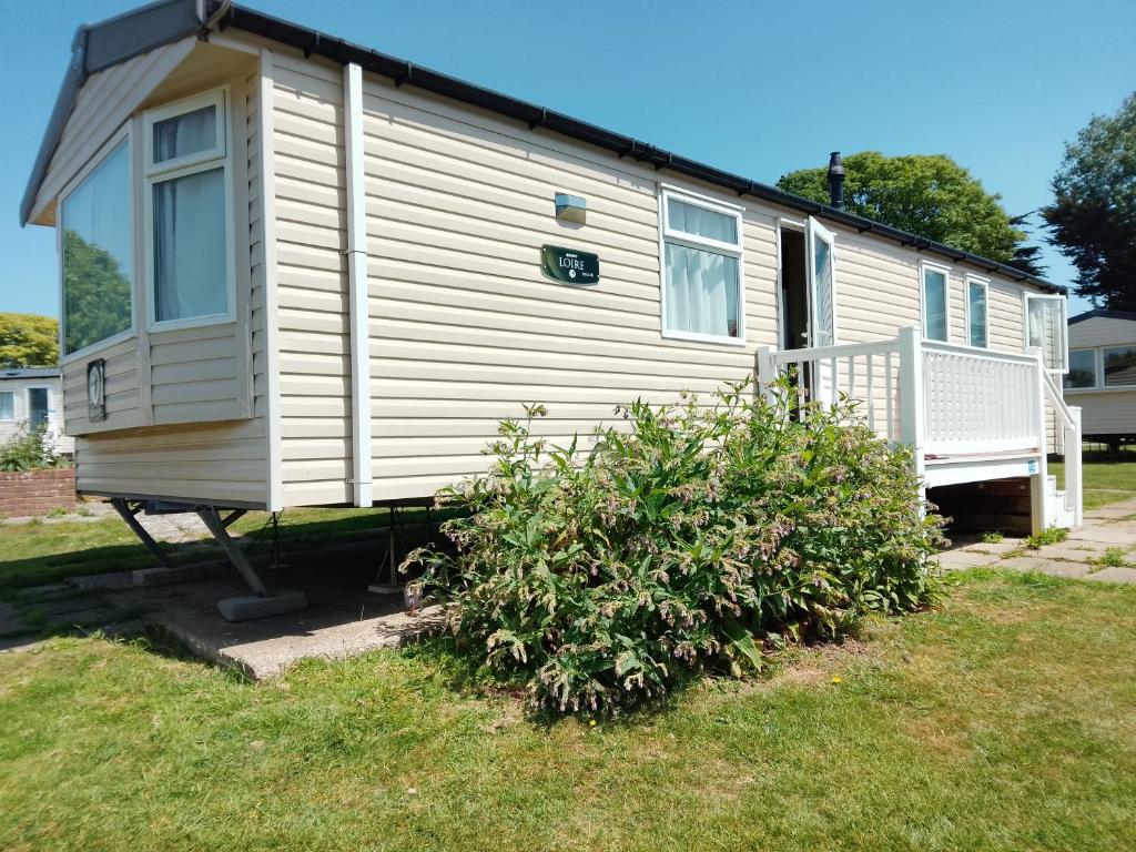 a white house with a bush in front of it at Weymouth Bay Holiday Static Caravan in Preston