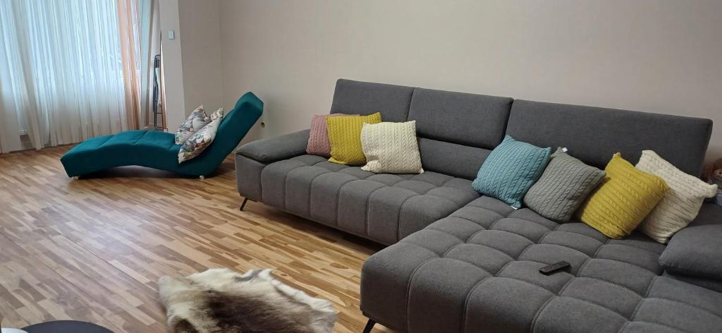 a living room with a gray couch with colorful pillows at Шанс in Velingrad