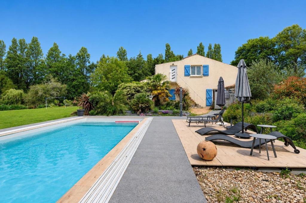 a pool with a table and chairs next to a house at Gite Douceur de vivre in Saint-Avaugourd-des-Landes