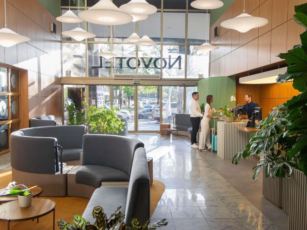 a lobby of a showroom with people standing at a counter at Novotel Porto Alegre Tres Figueiras in Porto Alegre