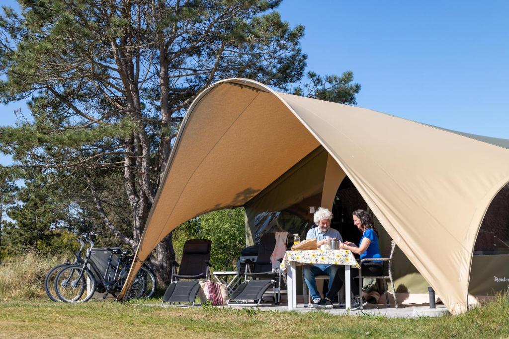 two people sitting at a table in a tent at Duynlodge Ameland direct aan het strand in Nes