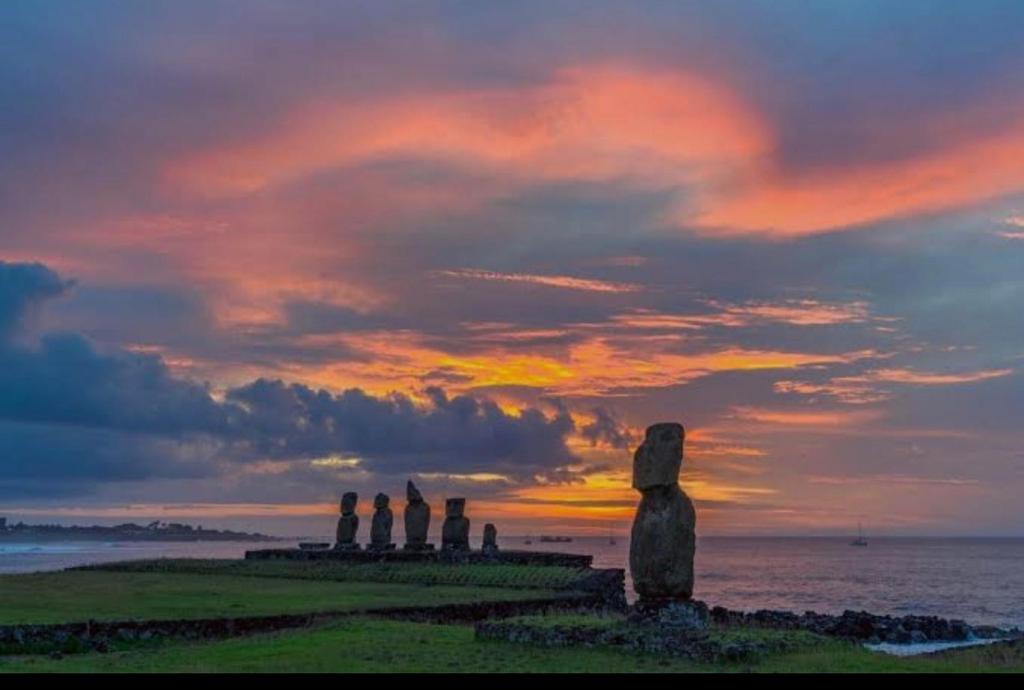 a group of statues in front of the ocean at sunset at Hare Maohi in Hanga Roa