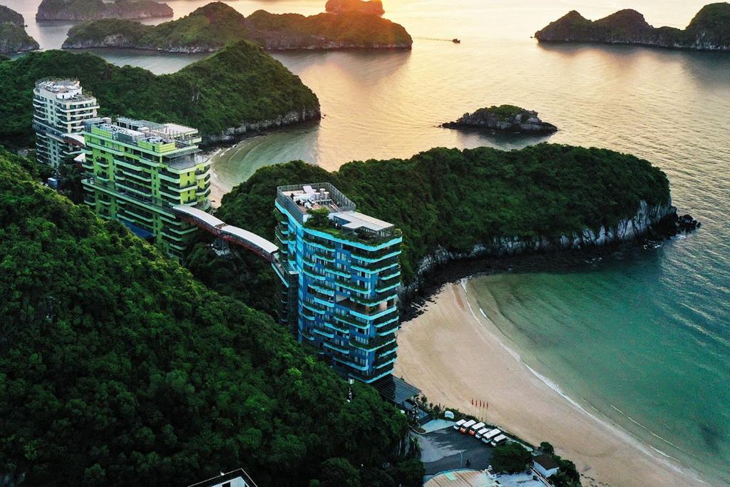 a group of buildings on a beach next to the water at Chốn Mộc - Cát Bà Resort in Cat Ba
