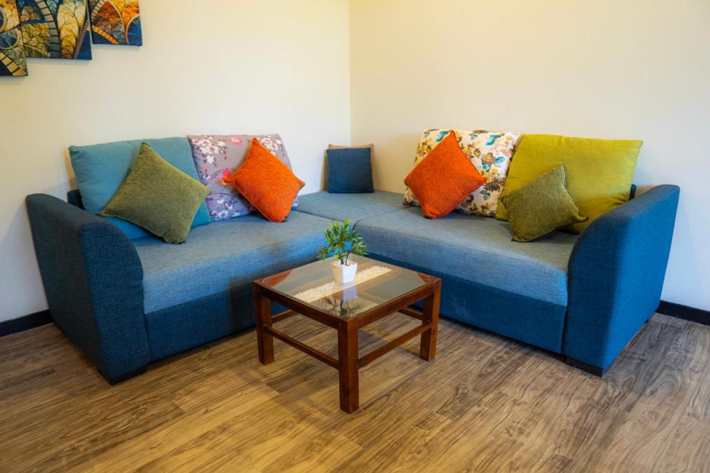 a blue couch with colorful pillows and a coffee table at Diana Residence in Matara
