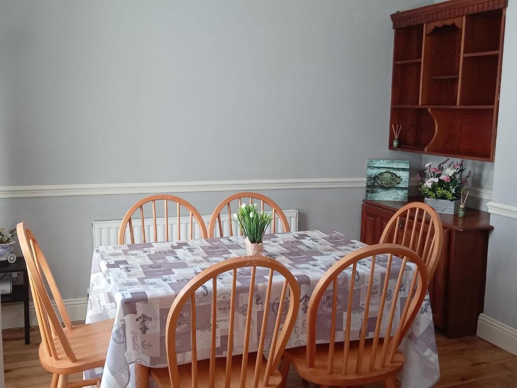 a dining room table with four chairs and a table with flowers on it at Comfy Home in Castlebar