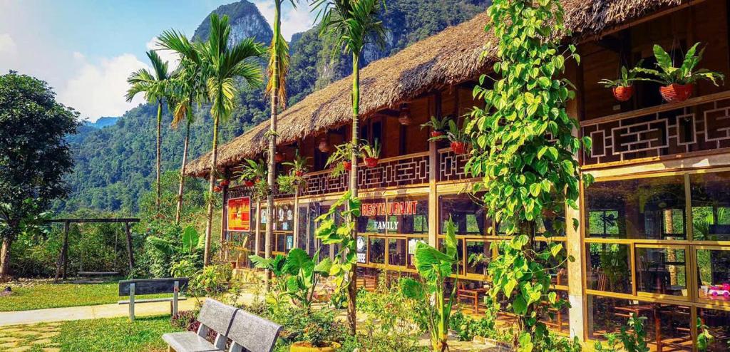 a building with a thatch roof and two benches at Homestay Xuân Sơn 2 in Phú Thọ