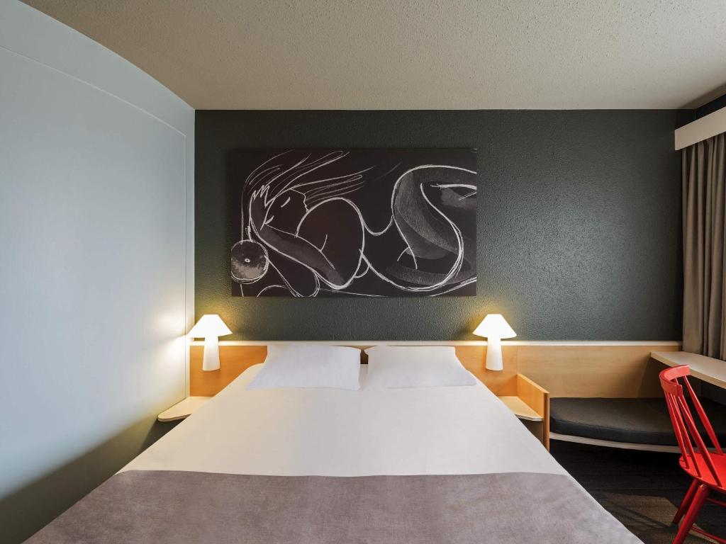 a bedroom with a bed and a painting on the wall at ibis Hotel Berlin Spandau in Berlin