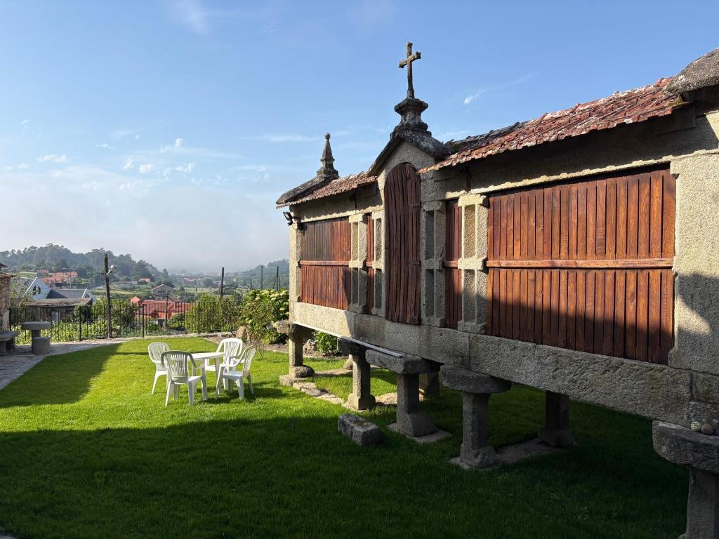 a house with two chairs and a table in a yard at Casa de Gándara in Baiona