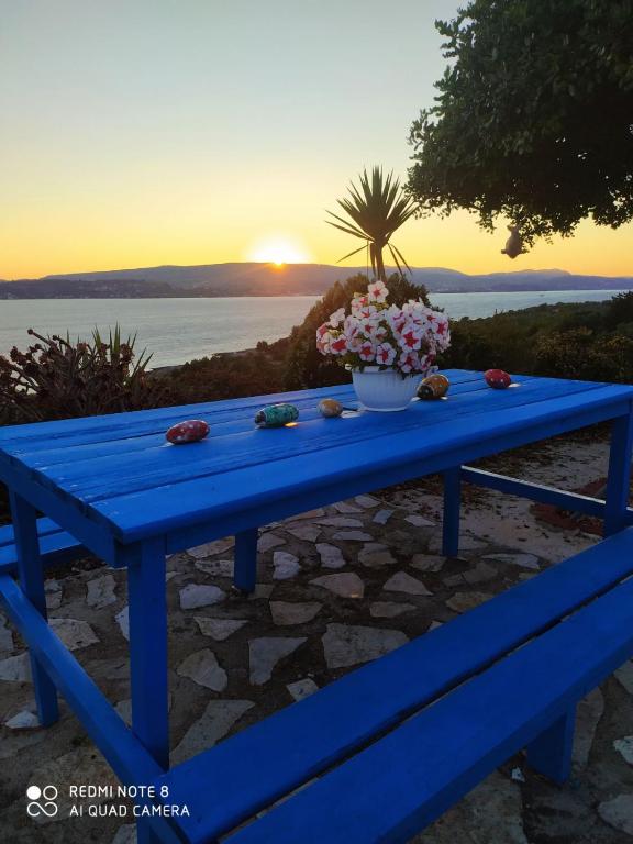 a blue picnic table with a vase of flowers on it at ARGOSTOLI sunset in Argostoli