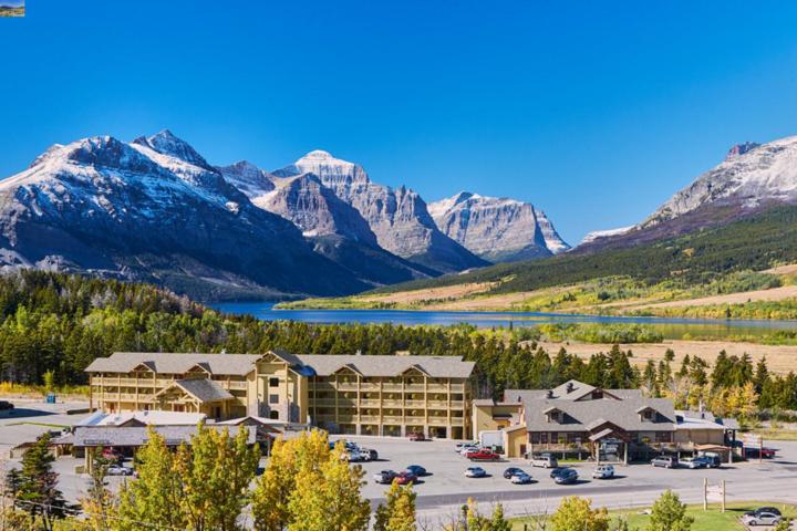 a hotel with a parking lot in front of a mountain at St. Mary Village in Saint Mary