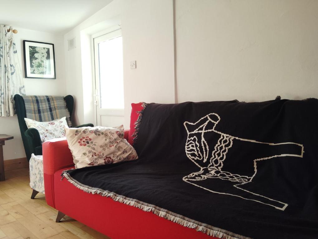 a red couch with a black blanket on it at New Ross Farm Cottage in New Ross