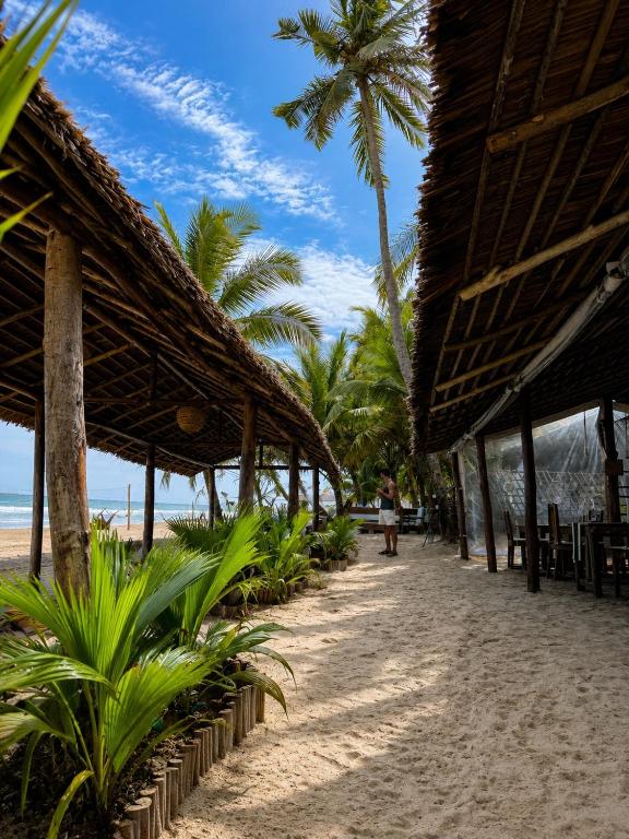 a beach with palm trees and a person walking on the sand at O'Sole Mio Assinie in Assinie