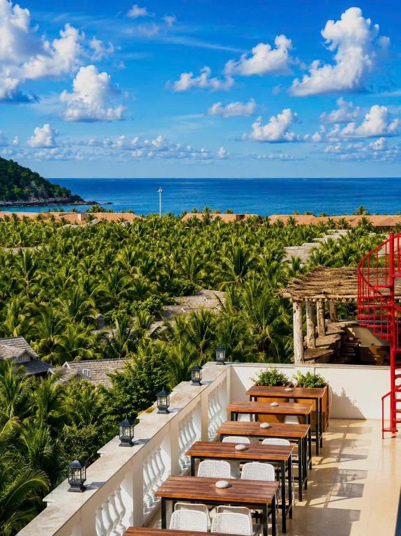 a row of tables with the ocean in the background at Vistalago Hotel Khem Beach Phu Quoc in Phú Quốc