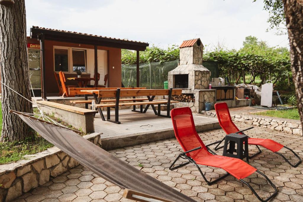 a patio with a hammock and a table and chairs at Vikendica Trebižat river in Čapljina