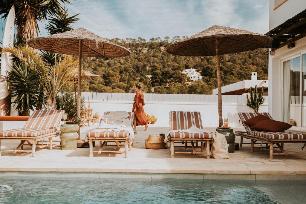 a patio with chairs and umbrellas next to a swimming pool at Casa Stellar - boutique villa with private pool and sea view - sustainably solar powered in Sant Josep de sa Talaia